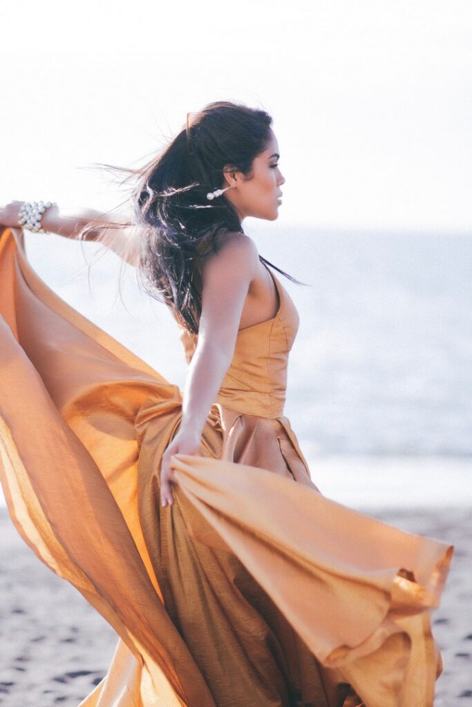 Woman dancing at the beach and wearing yellow dress